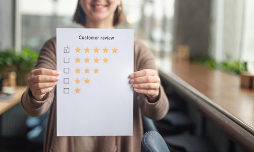 Unrecognizable woman showing five stars evaluating coworking place, blurred background, copy space